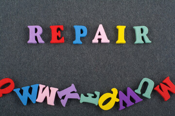 REPAIR word on black board background composed from colorful abc alphabet block wooden letters, copy space for ad text. Learning english concept.
