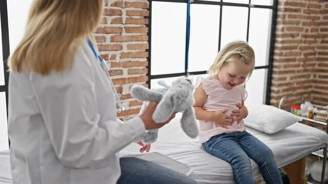 Happy child patient with rabbit toy in pediatric clinic, having joyful medical checkup with the confident woman doctor