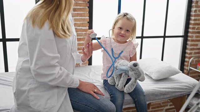 Adorable kid play-examining with doc using stethoscope at clinic, best moment in pediatric healthcare