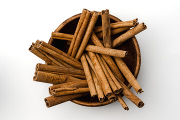 wooden bowl full of cinnamon stick with detail texture, isolated on white background, top view