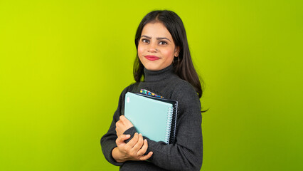 Fototapeta premium Young Indian student woman holding note books over isolated green screen chroma key background