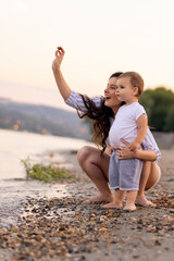 Mother and toddler son having fun throwing pebbles into river