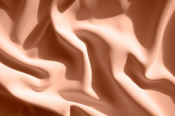 Texture of silk fabric lying in waves. Flat lay style, close-up. Trendy color of year 2024 - Peach Fuzz.
