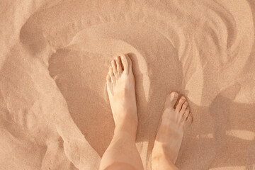 female feet on the sand on the beach. Woman on vacation. Color of the year 2024 Peach Fuzz.