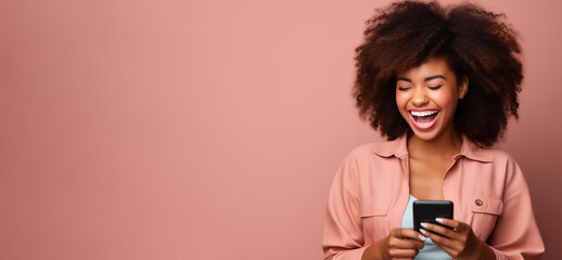 African american woman with phone in hands laughing on pink background