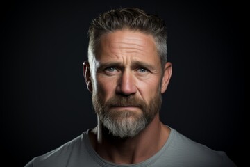 Portrait of a handsome mature man with a beard and mustache on a dark background. - obrazy, fototapety, plakaty
