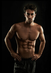 Fototapeta na wymiar Confident, black background or portrait of man with six pack, strong abs or stomach in studio for fitness. Cool, model or ripped person with healthy body, dark shadow or abdomen muscle for wellness