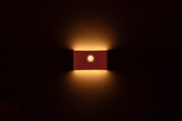 The lamp shines with warm light on the wall. Warm lighting.