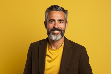 Portrait of happy mature man with beard and mustache on yellow background