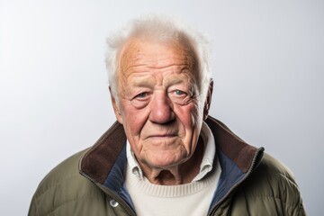 Portrait of an elderly man in a warm jacket on a gray background