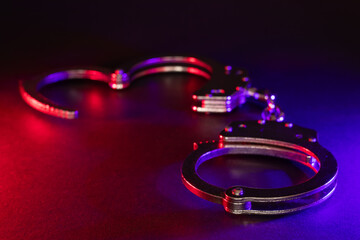 Closed handcuffs on the street pavement at night with police car lights high contrast image