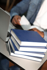 Experienced male teacher preparing for lesson at desk with books. Male businessman in modern office at desk with laptop