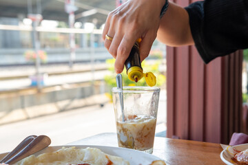 Woman's hand pouring sauce into breakfast