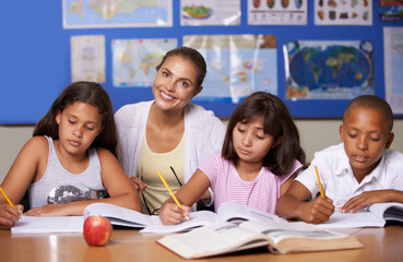 Teacher, portrait and school kids in classroom, writing or learning together for development, studying or knowledge. Woman, children and notebook with support, teaching and education with smile