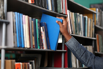 In a modern bookstore, the customer takes the book he likes off the shelf. Close-up of an African...