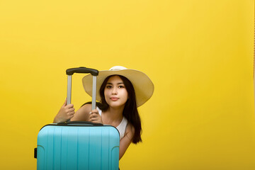 An Asian model poses in a straw hat with a large blue travel suitcase. A young woman with a serious...