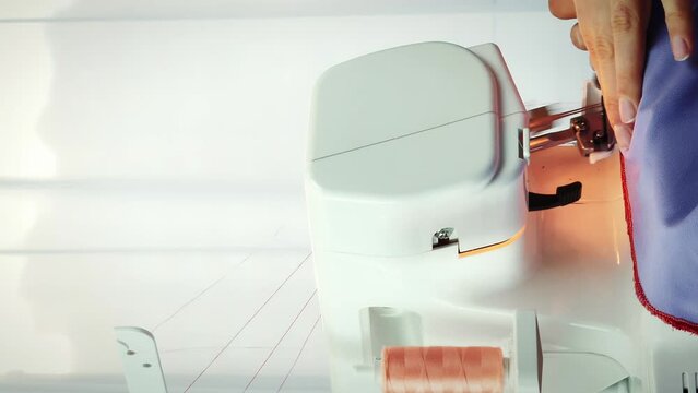 Female works on overlock in tailor's studio. Sewing machine. Vertical video
