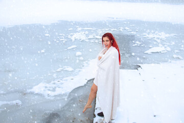 Ice woman dipping foot into cold water while snowing