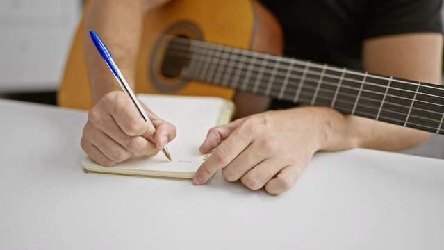 Attractive young hispanic man, a music studio composer artist, captivated by the melody while composing a classic song on his cherished acoustic guitar