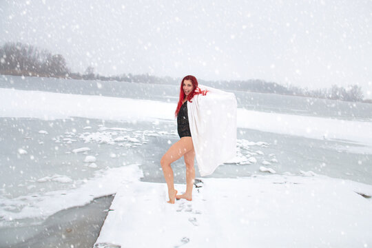 Cold-hardening woman in winter snowfall with bare legs on snow
