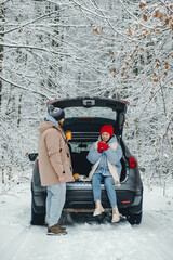 A couple stopped in a snowy forest to drink bitter tea and rest from the road