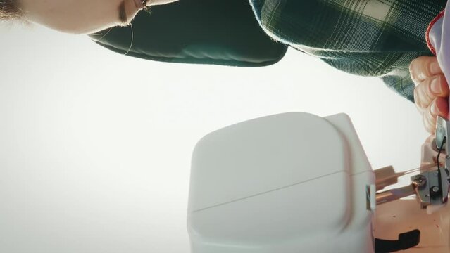 Female works on overlock in tailor's studio. Sewing machine. Vertical video