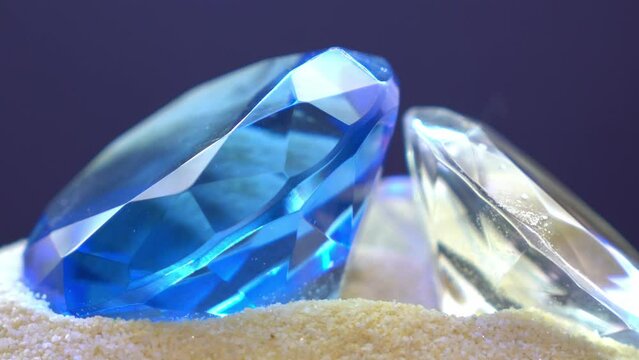 Blue diamond against a black background in the studio on sand, 4K