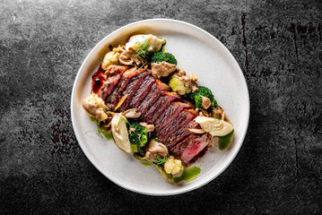 Cooked sliced beef steak rare with green broccoli.