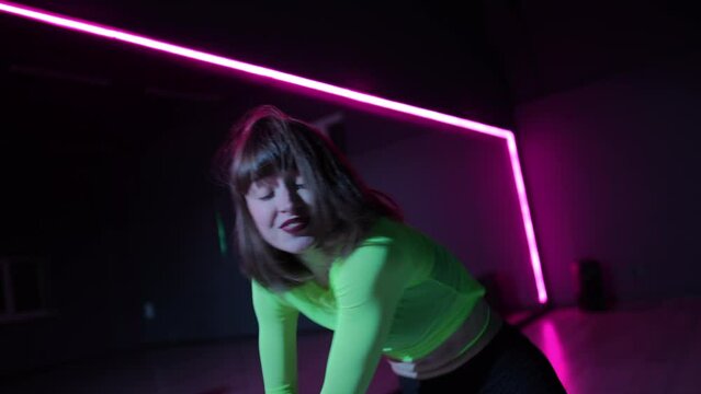 Live camera. A girl dancing twerk in a bright stage costume in a dark dance hall with neon lighting