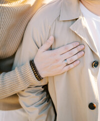 Man hugs his partner from behind with his hand on his chest. Cropped. Faceless