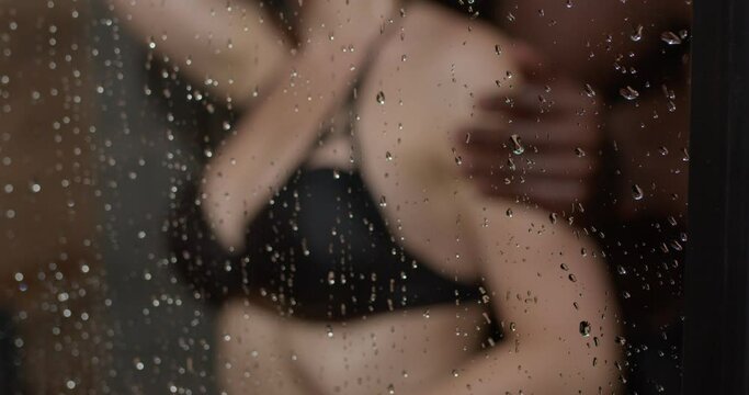 Loving affectionate woman leaned on glass in shower, having intimate moment with boyfriend. Close-up photo of elastic buttocks in black swimsuit rear view. sex, relationships, passion. copy space