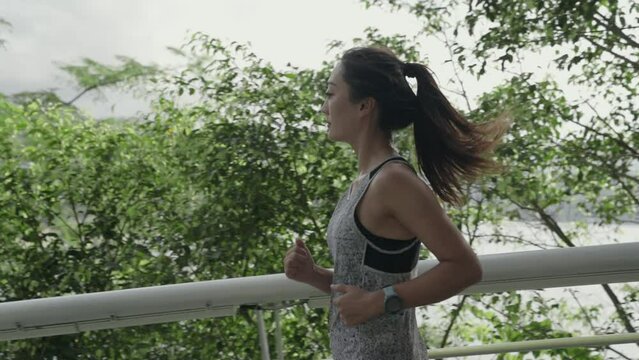 young asian woman female jogger running exercising outdoors in park by the sea
