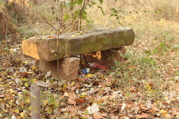 A Slab or old stone bench in the middle of grass and trash 