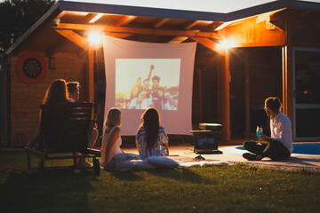 Friends having fun in home backyard open air cinema watching a movie