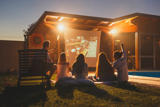 Friends watching a movie in an open air cinema waving with sparklers
