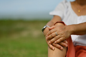 Close-up middle-aged female hands on knees while sitting in a kneeling position