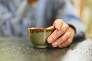 Close-up and cropped male hand holding a small cup of tea, Traditional Asian tea cup, Concept...