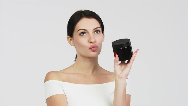 Portrait of a charismatic young woman using face creams. Concept of fresh moisturized skin, beautiful cosmetic face, happy healthy model. A young brunette takes care of her skin.