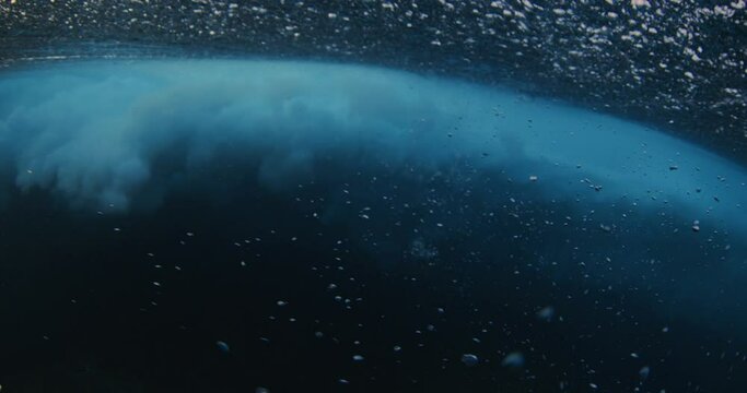 Underwater view of the ocean wave breaking with lots of foam and bubbles