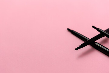 Abstract defocused beauty concept made with set black eyeliners or black pencils on the pink background