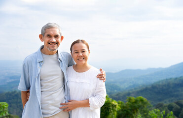 Obraz premium portrait romantic senior couple embracing,smiling,standing in summer landscape, asian older adult people spend holiday summertime traveling in nature