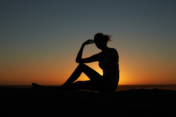 Sunset, silhouette and woman at a beach relax, resting and enjoying quiet morning on sky...