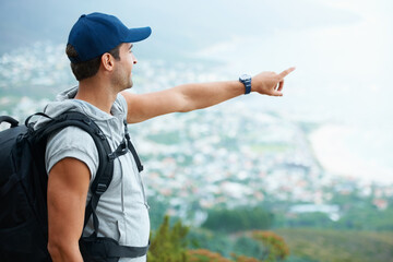 Outdoor, hiking and man with nature, pointing and adventure with direction, journey and fitness. Person, hiker and guy with wellness, travel or location with fresh air, forest or landscape with view