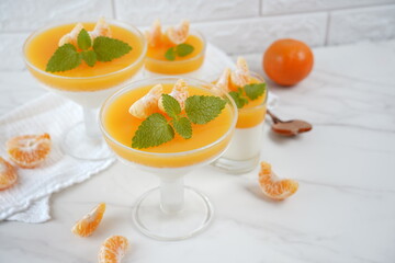 Vanilla panna cotta with tangerine layer in a small portioned vase and fruit pieces in wineglasses....