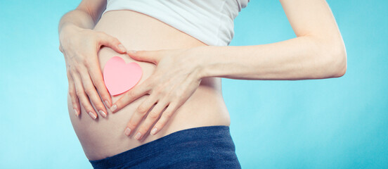 Fototapeta na wymiar Woman in pregnant with pink heart on her belly. Expecting for newborn. Extending family