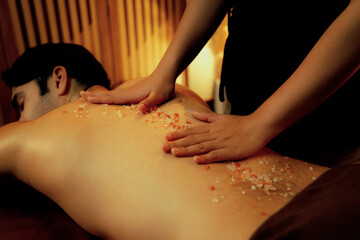 Man customer having exfoliation treatment in luxury spa salon with warmth candle light ambient....