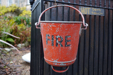 Old vintage fire bucket hanging on fence railings. metal sand or water bucket 