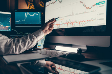 Close-up of male trader pointing computer monitor while analyzing stock market charts in office
