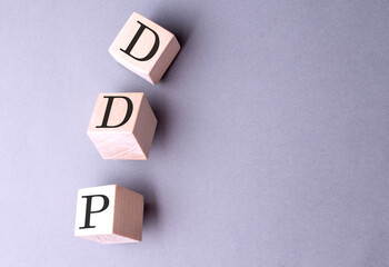 Word DDP on wooden block on the grey background