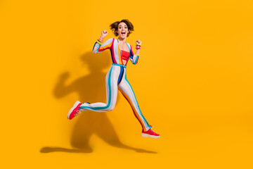 Photo of positive crazy excited girl jumping fists up enjoying discounts isolated bright color background
